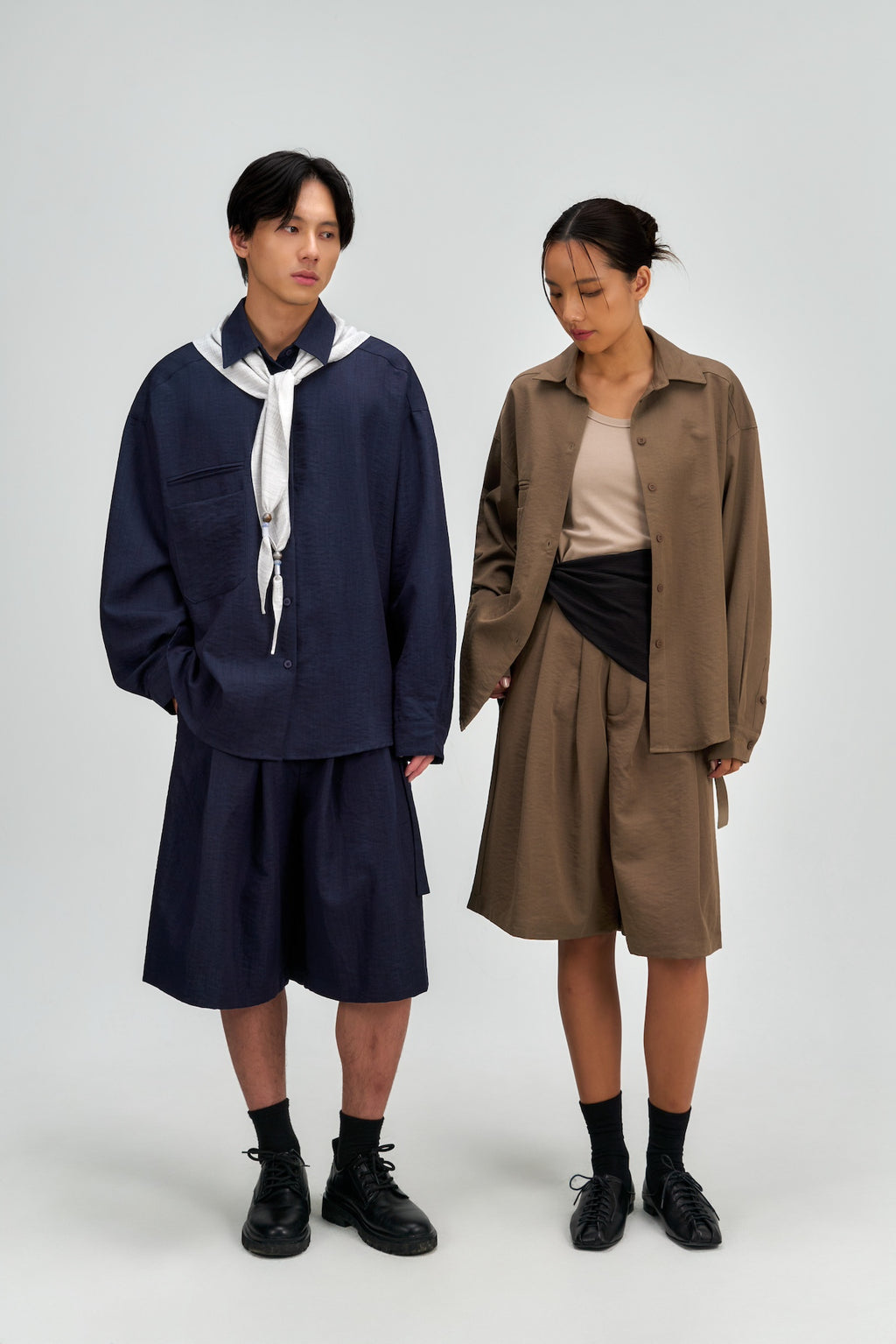 Two people wearing matching outfits with a plain background